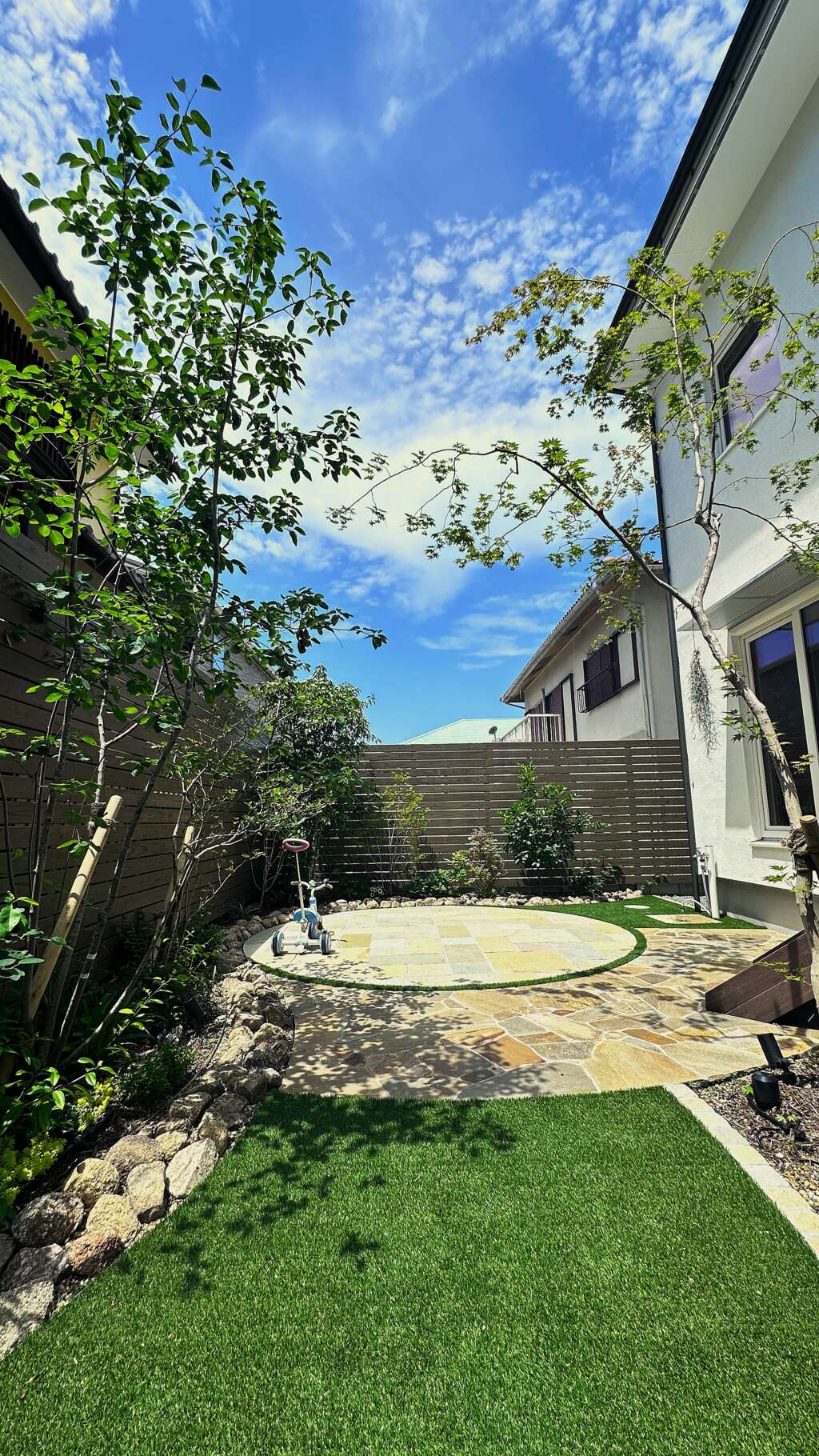 空の青、樹木の緑、庭の石。幾何学模様と自然の模様が重なって見える景色。